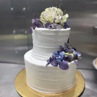 a three tiered white cake with purple flowers