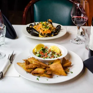 two plates of food and a glass of wine