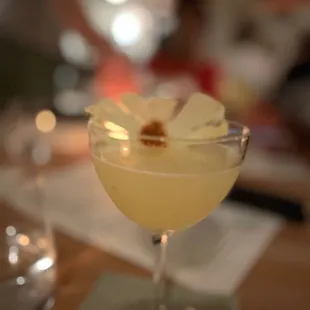 a cocktail in a glass with a flower garnish