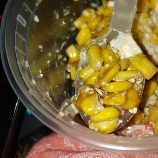 a bowl of corn with a spoon in it