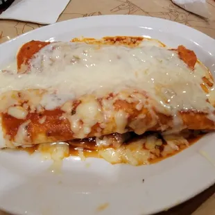 Two chicken burritos with red sauce and cheese