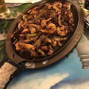 Sizzling Mixed fajitas shrimp chicken beef and chorizo deliciously sautéd together
