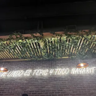 a brick wall with a neon sign that reads the lord&apos;s help you narrat