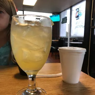 a girl sitting at a table with a drink