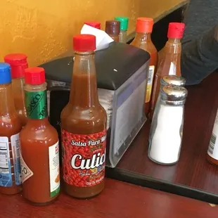 a table full of hot sauces and condiments