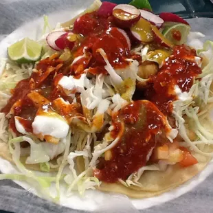 Four fish tacos with red hot sauce.