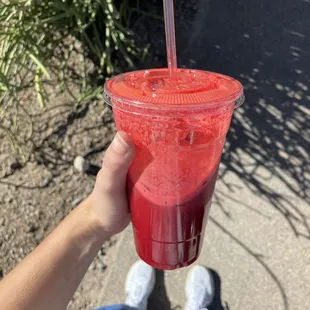 a hand holding a red drink