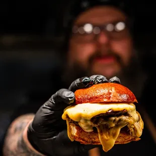 a tattooed man holding a cheeseburger