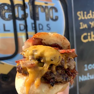 a hand holding a cheeseburger