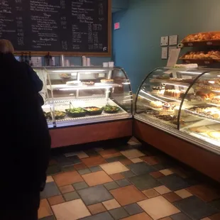 a woman standing in front of a display of pastries