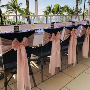 Simple pretty pink sashes adds a sweet touch to these wicker chairs attire Tiki's Grill and Bar!