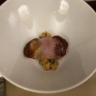 a white bowl with a piece of meat in it