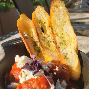 a bowl of food with bread and sauce