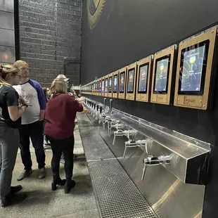 a group of people standing in front of a row of sinks
