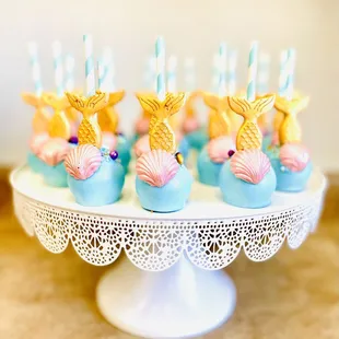 a plate of cake pops decorated like mermaids
