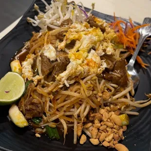 a plate of noodles with meat and vegetables