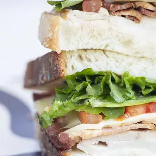 A classic turkey club: Turkey, bacon, Swiss, tomato, lettuce and mayonnaise on rustic white bread