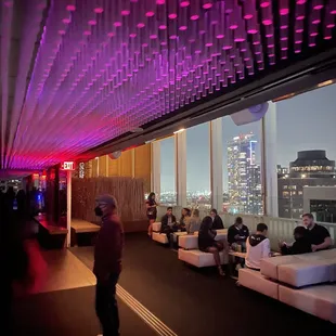people sitting on couches in a room with a view of the city