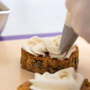 a person spreading icing on a piece of cake