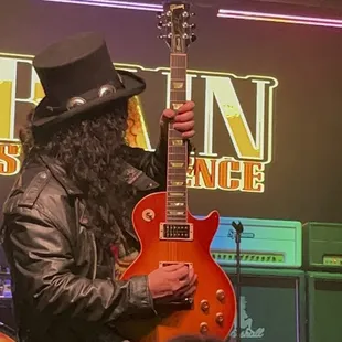 a man in a top hat playing a guitar