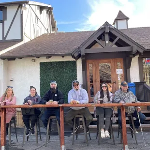 a group of people sitting at a table outside a restaurant
