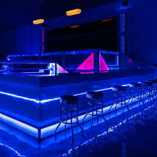 a bar with stools and neon lights
