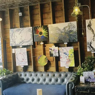 a living room with a blue couch and several paintings on the wall