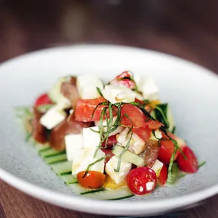 a plate of salad with cucumbers and tomatoes