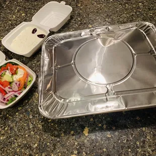 a tray of salad and a container of dressing