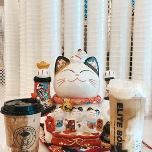 a cat statue and cups of coffee