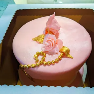 a pink cake with gold decorations