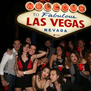 a group of people posing in front of a welcome to fabulous las sign