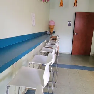 a row of white chairs and a blue counter