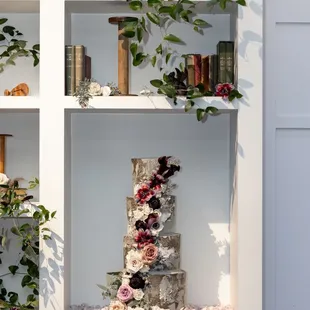 a three tiered cake on a bookcase