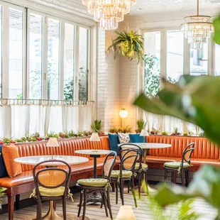 a dining room with orange velvet banquet seating and a chandelier