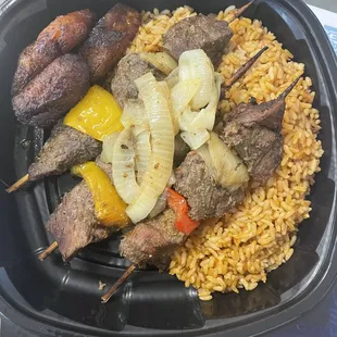 Beef Kabob Over Jollof Rice topped with Sauté Onions and Plantain.