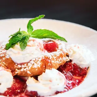 a plate of dessert with whipped cream and strawberries