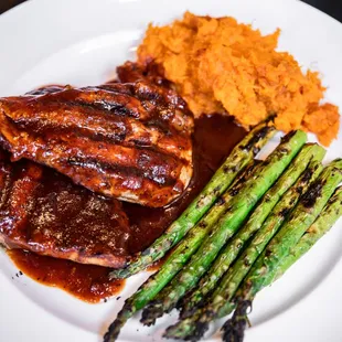 a plate of meat, asparagus and mashed potatoes