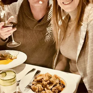 a man and a woman sitting at a table with food