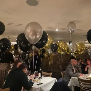 a group of people sitting at a table with balloons