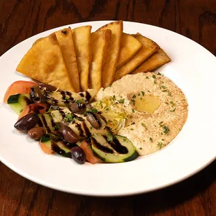 Hoppin&apos; Hummus: Tahini and garlic hummus topped with fresh parsley and garlic olive oil. Served with balsamic drizzled Kalamata olives.