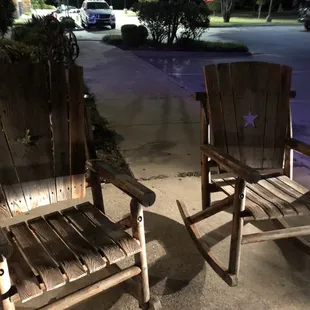two wooden chairs on a sidewalk