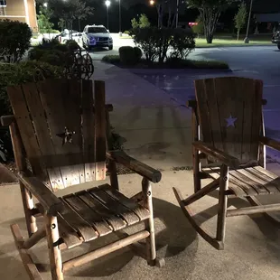 two wooden rocking chairs in a parking lot