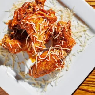  a plate of chicken wings with gravy and parmesan cheese