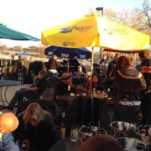 a group of people sitting at tables under umbrellas
