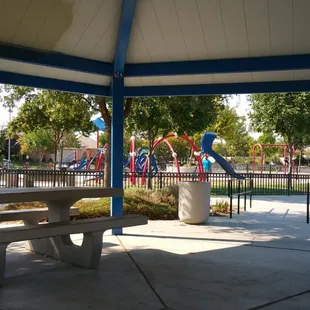Under the gazebo, facing the playground.
