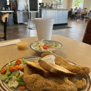 a plate of fried chicken with a side salad