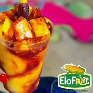 a hand holding a cup of fruit and ice cream