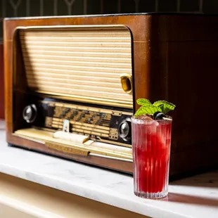 an old radio and a drink on a counter