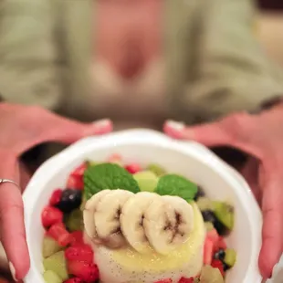 a woman holding a bowl of fruit